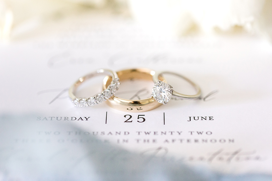 engagement ring and wedding bands photographed on wedding invitation